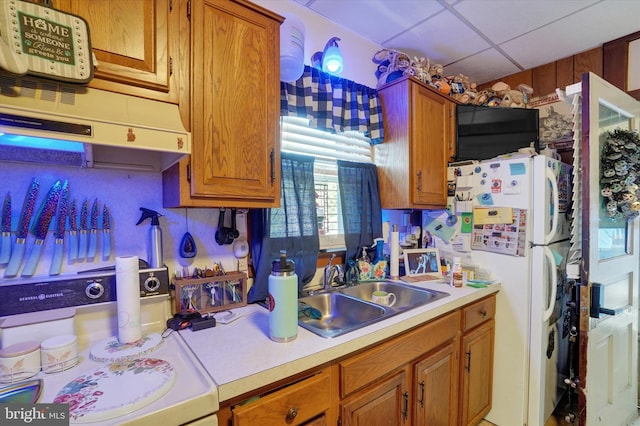 kitchen with range, white fridge, a drop ceiling, and sink