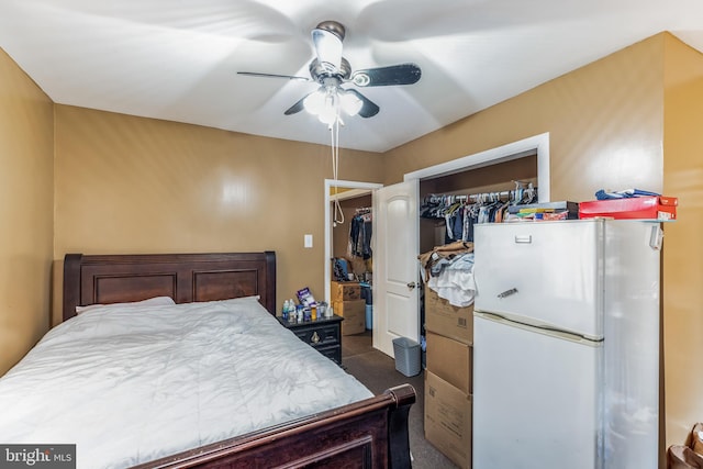 carpeted bedroom with a closet, white refrigerator, and ceiling fan