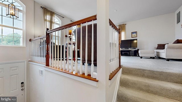 stairway featuring carpet flooring and an inviting chandelier