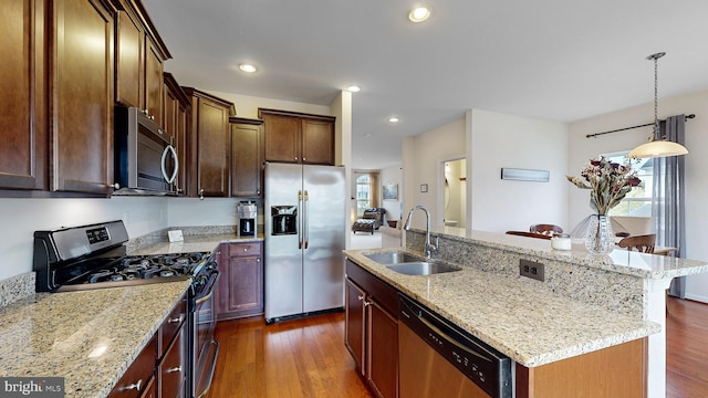 kitchen featuring hanging light fixtures, sink, a center island with sink, dark wood-type flooring, and appliances with stainless steel finishes