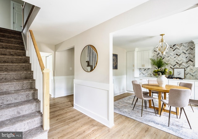 dining room with light wood-type flooring and an inviting chandelier