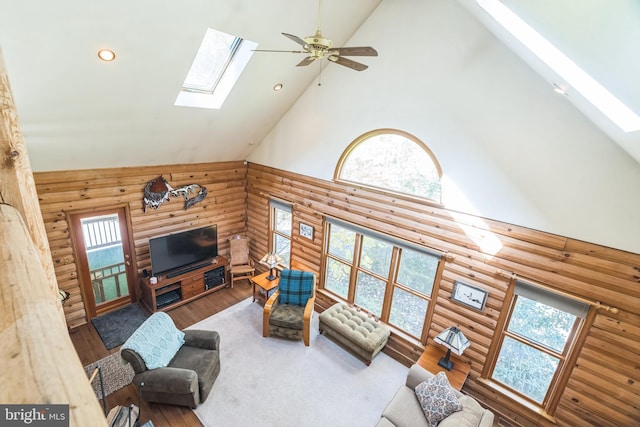 living room featuring high vaulted ceiling, hardwood / wood-style floors, a skylight, and a healthy amount of sunlight