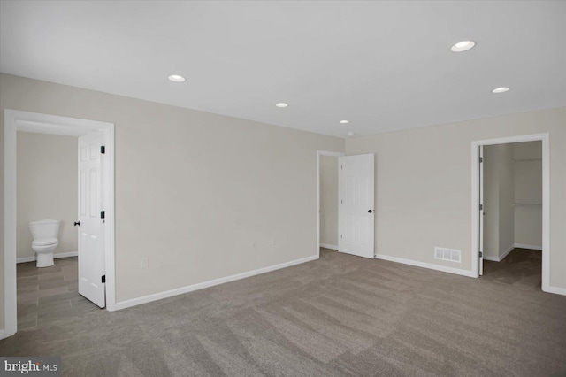 unfurnished bedroom featuring a spacious closet, ensuite bath, a closet, and carpet