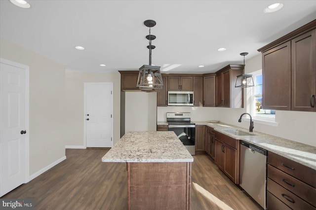 kitchen featuring decorative light fixtures, sink, a center island, light stone counters, and stainless steel appliances