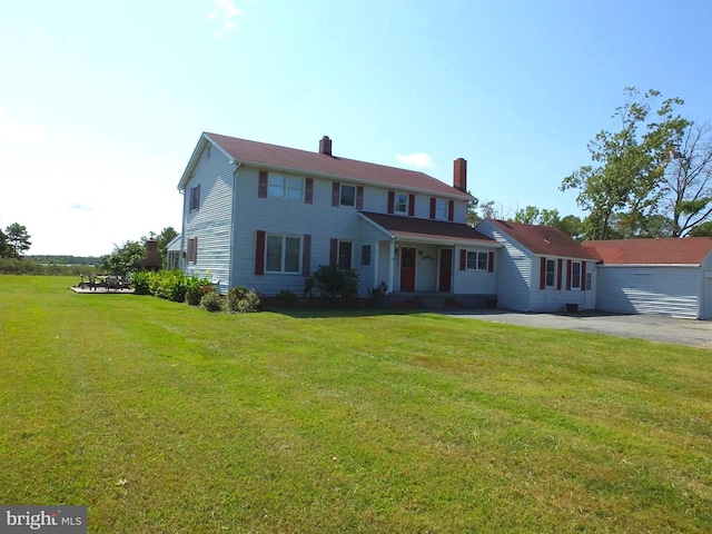 colonial home with a chimney, driveway, and a front lawn
