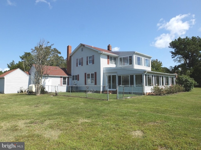 back of property with a sunroom and a yard