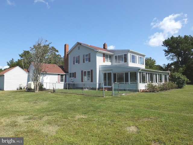 rear view of house with fence, a sunroom, a chimney, and a lawn