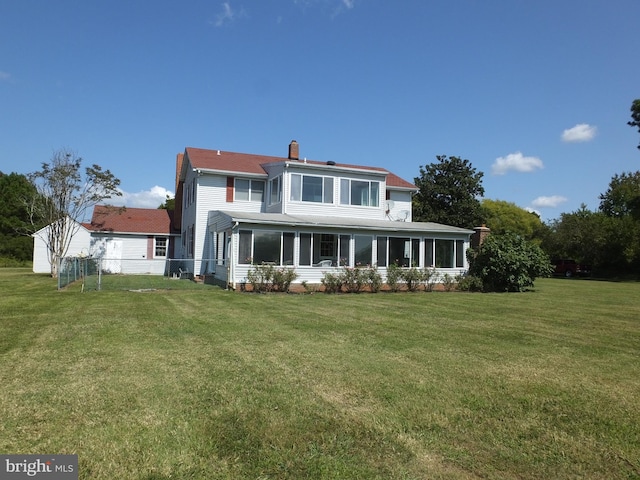 back of property featuring a yard, a sunroom, and a chimney