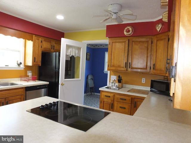 kitchen featuring ceiling fan, brown cabinetry, black appliances, a sink, and light countertops