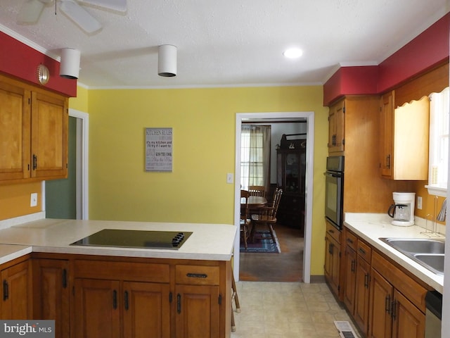 kitchen with light countertops, a wealth of natural light, visible vents, brown cabinets, and black appliances