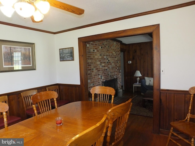 dining space featuring wooden walls, wainscoting, ornamental molding, and wood finished floors