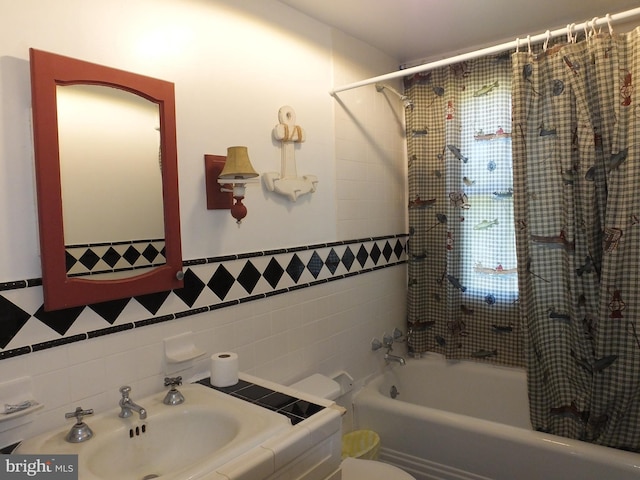 full bathroom with sink, tile walls, toilet, and shower / tub combo with curtain