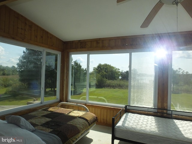 sunroom / solarium featuring wood walls, ceiling fan, and lofted ceiling