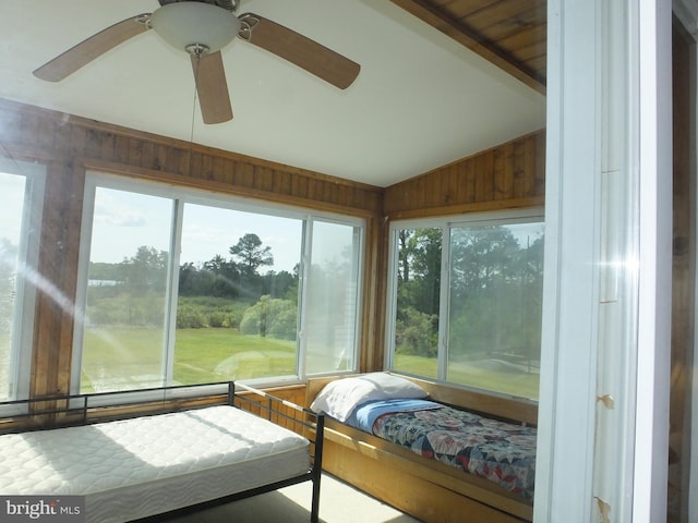 sunroom featuring wood walls and lofted ceiling