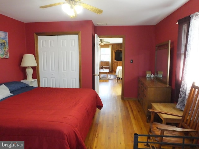 bedroom featuring a closet, light hardwood / wood-style floors, multiple windows, and ceiling fan