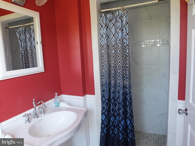 full bath with a tile shower, a sink, and wainscoting