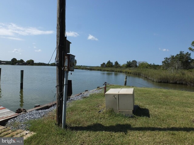 view of dock with a lawn and a water view