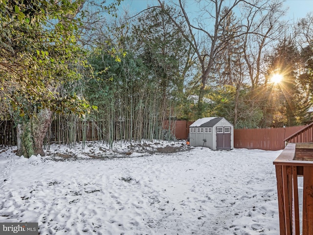 snowy yard featuring a storage shed