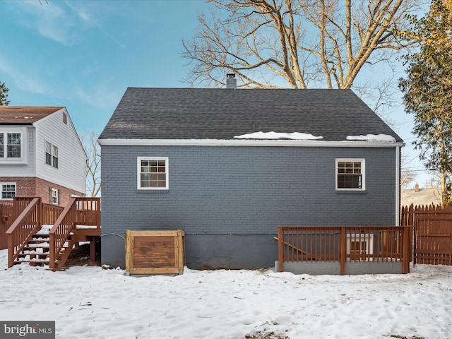 snow covered house featuring a wooden deck