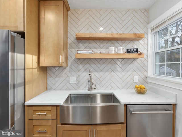 kitchen featuring stainless steel appliances, light stone countertops, tasteful backsplash, and sink