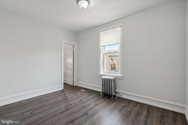 spare room with dark wood-type flooring and radiator heating unit