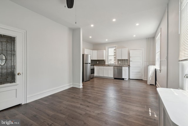 kitchen with dark hardwood / wood-style floors, tasteful backsplash, white cabinets, stainless steel appliances, and ceiling fan