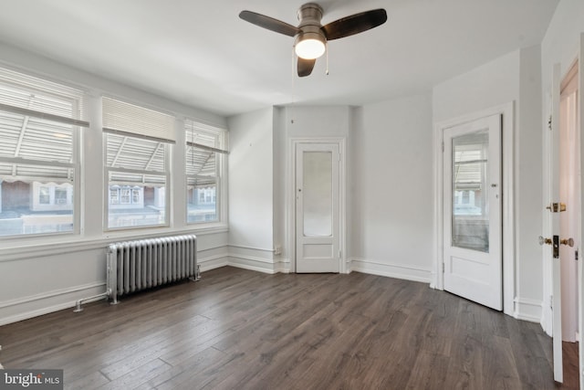 unfurnished bedroom with ceiling fan, radiator, dark hardwood / wood-style floors, and multiple windows