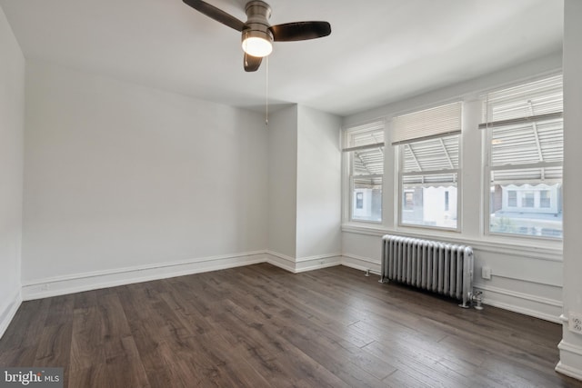 spare room with a healthy amount of sunlight, ceiling fan, radiator heating unit, and dark hardwood / wood-style flooring