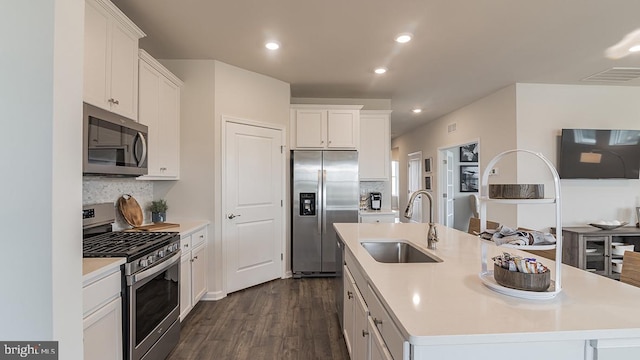 kitchen with stainless steel appliances, white cabinets, a center island with sink, and dark hardwood / wood-style floors