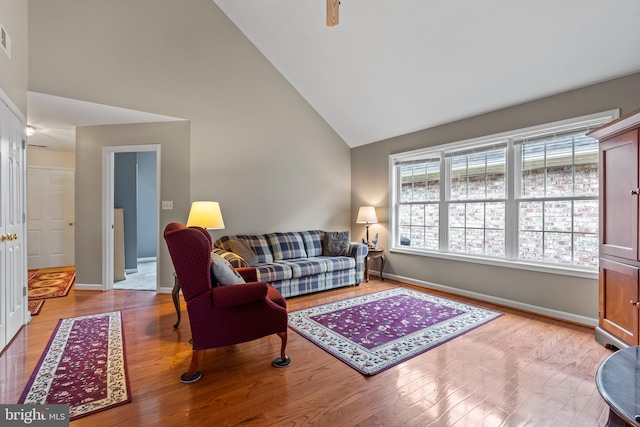 living room with light wood-type flooring and high vaulted ceiling