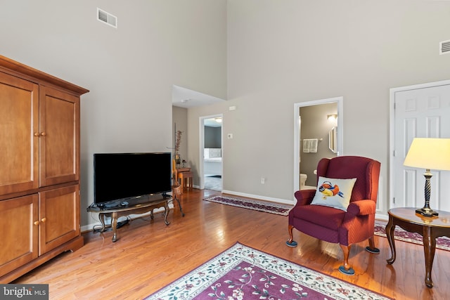 living area with light hardwood / wood-style flooring and a high ceiling