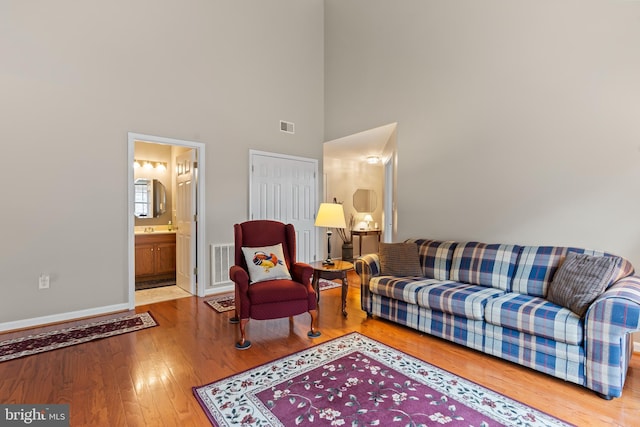 living room featuring hardwood / wood-style flooring and a towering ceiling