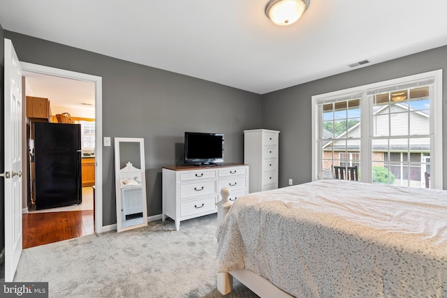 carpeted bedroom featuring black fridge and ensuite bathroom