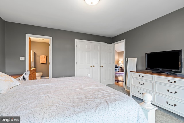 bedroom featuring light colored carpet, a closet, and ensuite bathroom