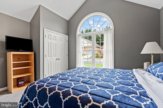 carpeted bedroom with a closet and vaulted ceiling