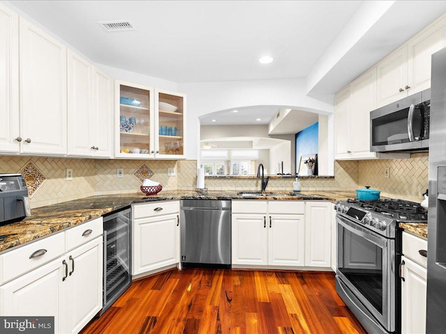 kitchen featuring dark stone countertops, appliances with stainless steel finishes, dark hardwood / wood-style floors, and sink