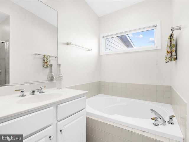 bathroom with vanity and a relaxing tiled tub