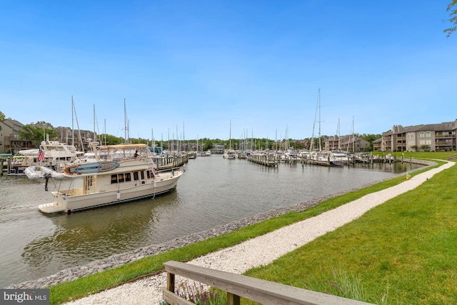 view of dock with a lawn and a water view