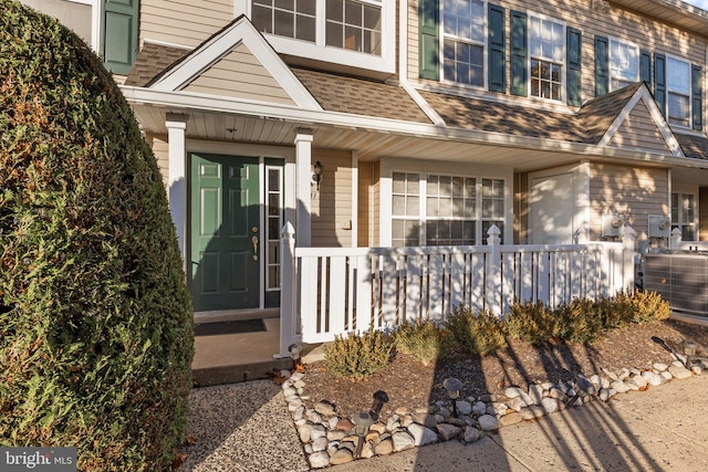 view of exterior entry featuring a porch and cooling unit