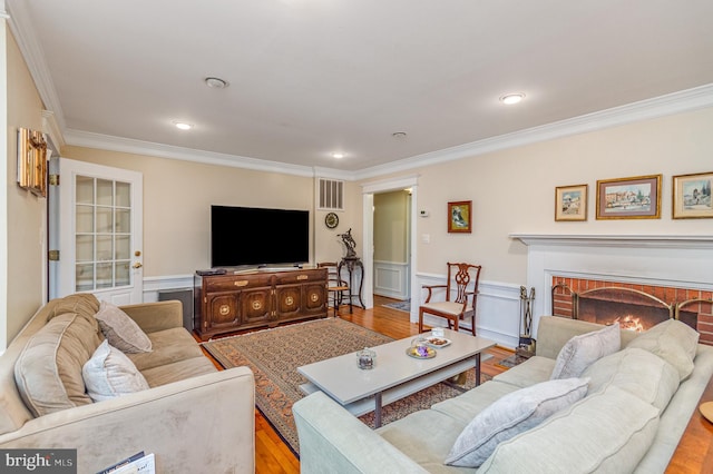 living room featuring a fireplace, light wood-type flooring, and ornamental molding