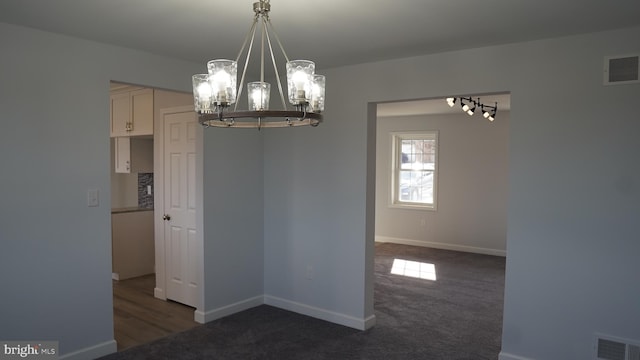 unfurnished dining area featuring dark colored carpet and a notable chandelier