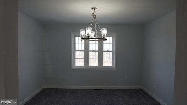 carpeted spare room with a notable chandelier