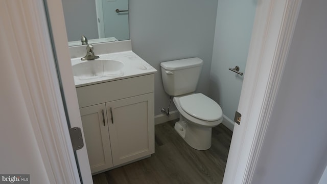 bathroom with wood-type flooring, vanity, and toilet