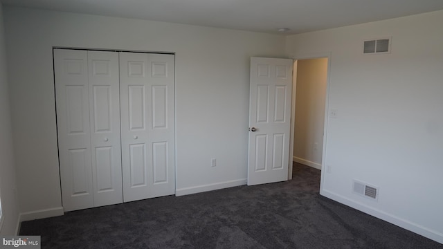 unfurnished bedroom with dark colored carpet and a closet