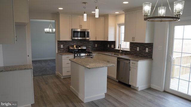 kitchen with appliances with stainless steel finishes, a kitchen island, sink, and an inviting chandelier