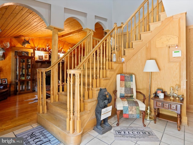 staircase featuring wooden ceiling, wood-type flooring, and wooden walls