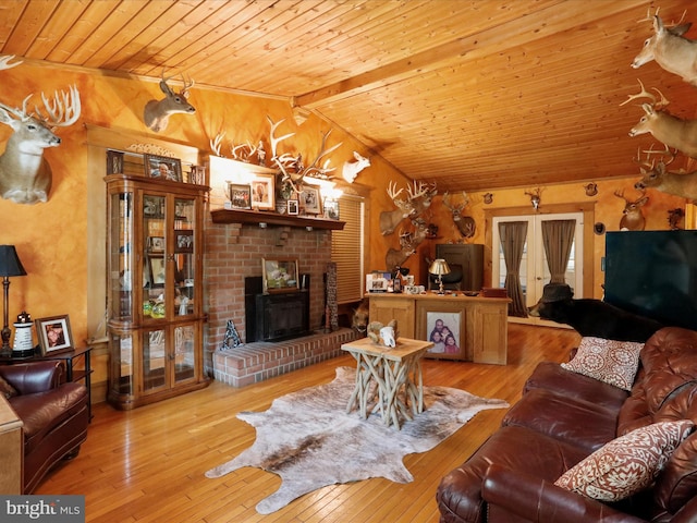 living room featuring vaulted ceiling with beams, a fireplace, light hardwood / wood-style floors, and wooden ceiling