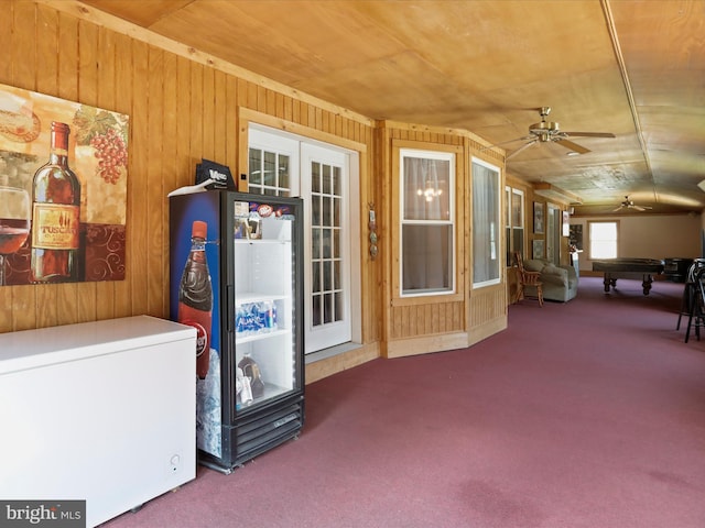 misc room featuring carpet, wooden walls, and ceiling fan