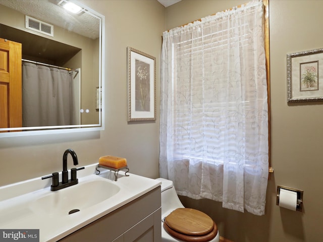 bathroom featuring a textured ceiling, vanity, and toilet