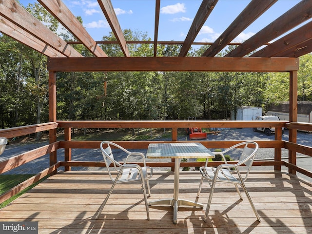 wooden terrace with a storage shed and a pergola